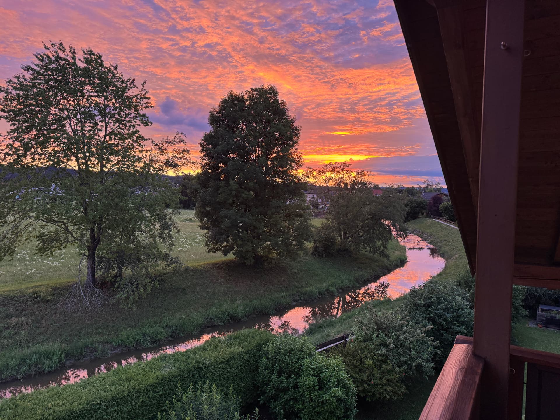 Sonnenuntergang über den Chiemgauer Alpen, gesehen vom Holzbalkon des Bergloft