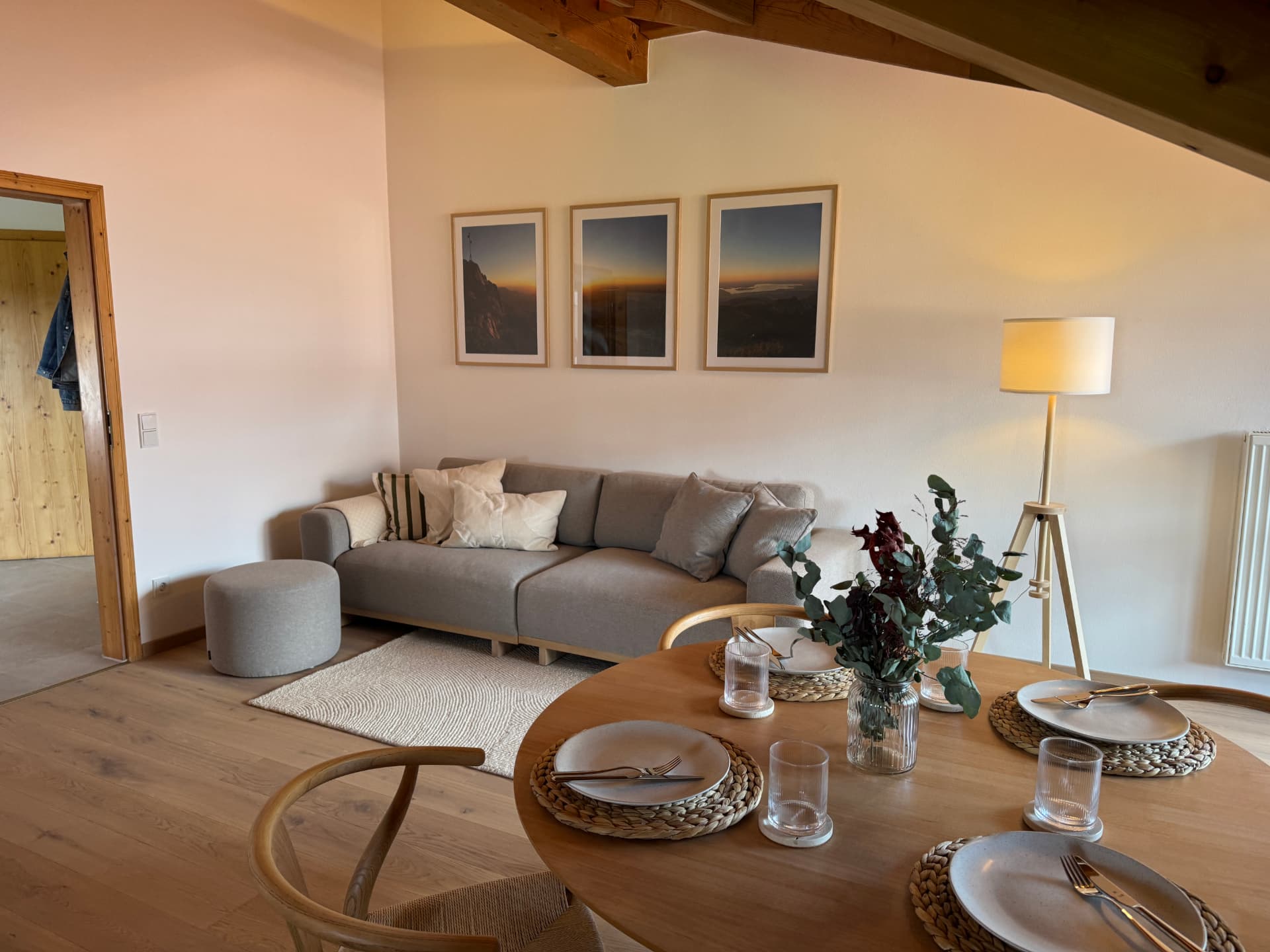 Gedeckter Esstisch vor dem Sofa mit Bergfotografien an der Wand