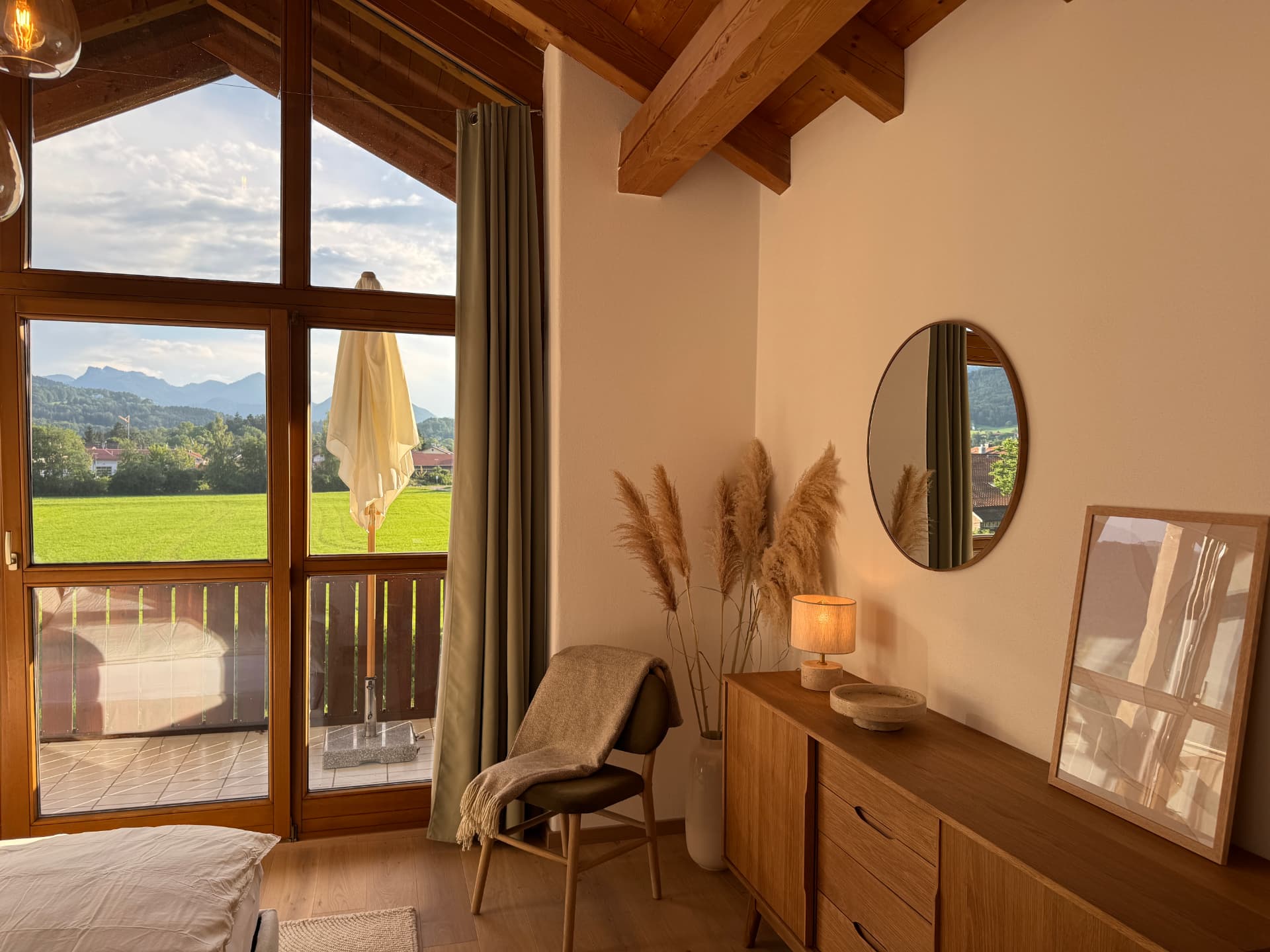 Schlafzimmer mit Eichensideboard, Rundspiegel und Balkonzugang